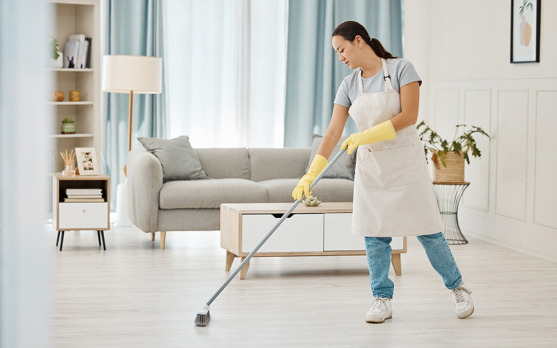 Ex-Singapore maid sweeping floor in modern living room setting.