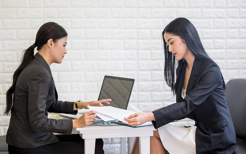 Employer reviewing hiring contract with maid agency representative.