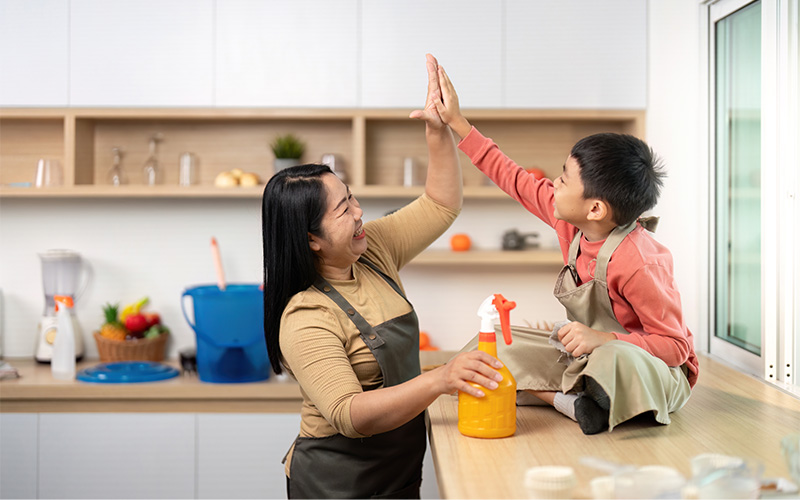 Two people share a highfive while tidying up the kitchen