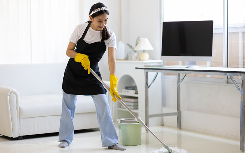 Young Asian woman cleaning the house with a mop